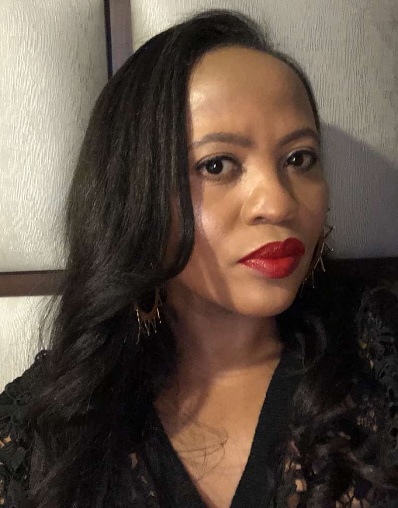 A profile shot of a Black female wearing a black jumper with red lipstick