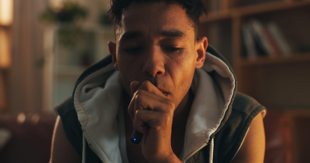 Drugs, addiction and man on sofa with anxiety, fear and withdrawal symptom in home at night. Nervous, thinking and person in crisis in dark apartment with stress, substance abuse and narcotic detox.