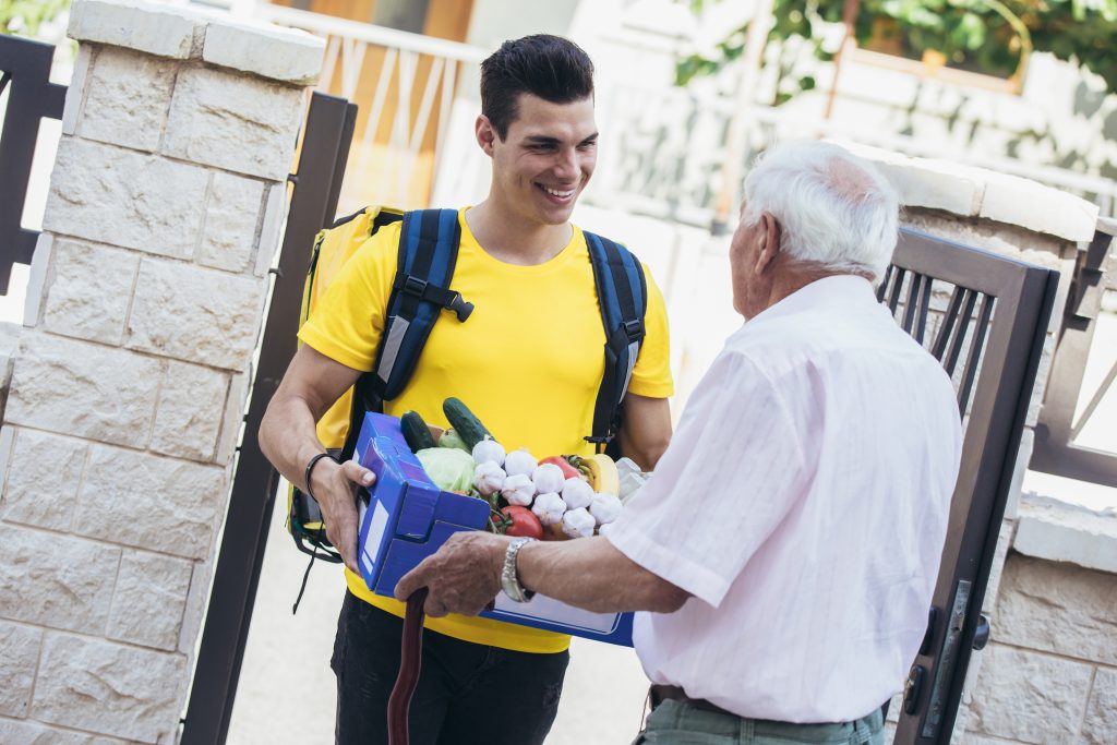 Young male volunteer delivering shopping to senior man. Donation