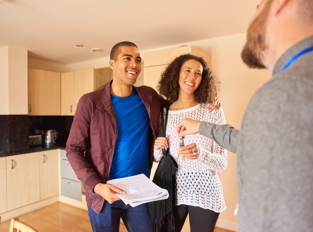 A couple standing in a kitchen sharing story with a white male