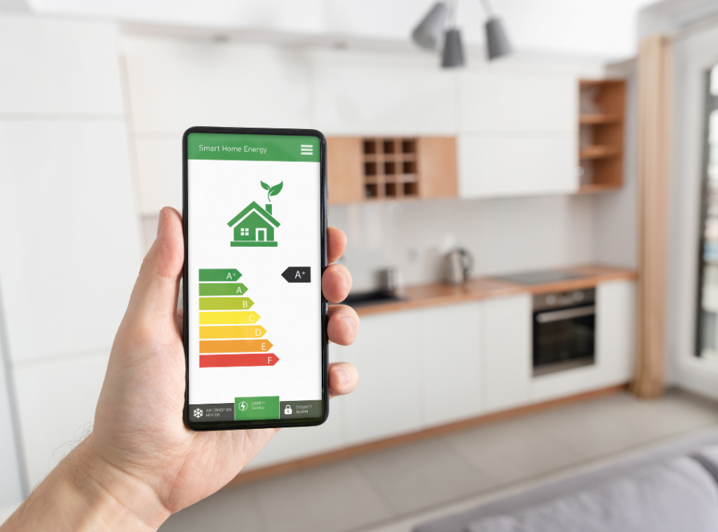 A white man holding their mobile in their kitchen showing how efficient their home is