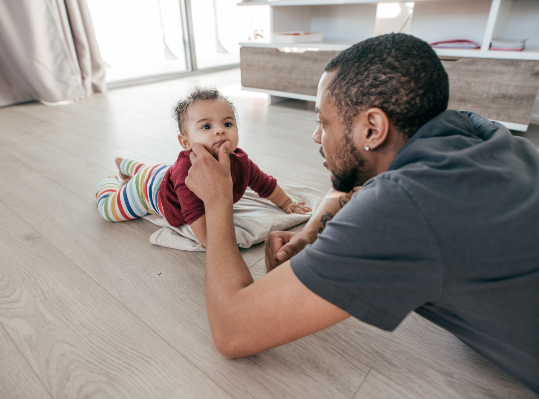 Black father playing with his baby on the floor