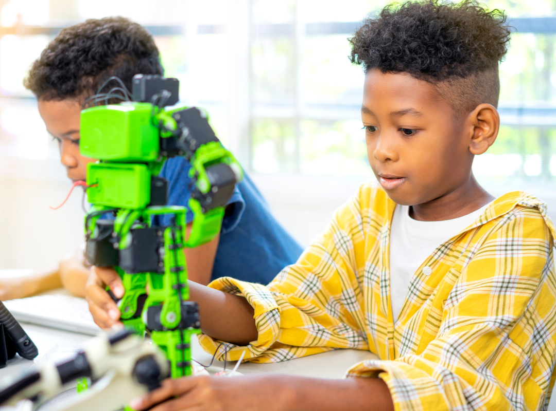 Two black boys one playing with a green robot