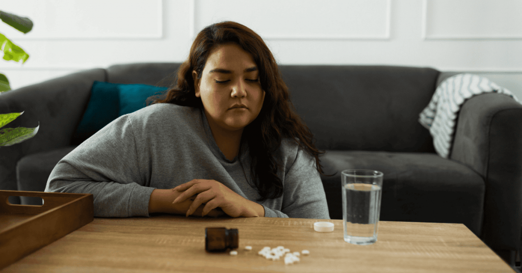 Woman with pills on the table with mobile phone with a glass of water